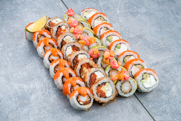 Set of japanese sushi rolls with tuna, salmon, shrimp, avocado, cream cheese, red flying fish caviar, sauce and lime.