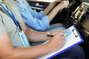 Driving school. Student passing driving test with examiner in car, closeup