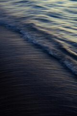Wave crashing onto beach sunset, long exposure