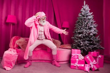 Photo of pensioner bearded male point excited gifts tree santa claus fancy boots fur coat fluffy nighty hat pink christmas decoration x-mas