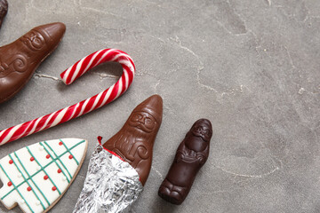 Chocolate Santa Clauses, cookie and candy cane on grunge background, closeup