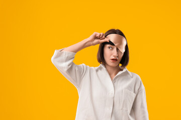 Overslept young woman with sleep mask on yellow background