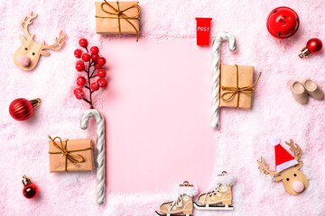 Frame made of gift boxes, candy canes and different Christmas decorations on snow against pink background