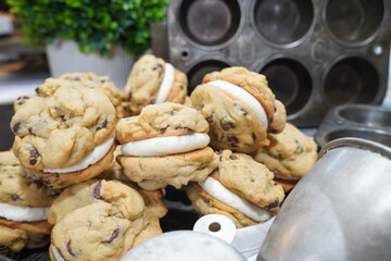 Homemade and freshly baked chocolate chip whoopie pies with vanilla buttercream frosting.  Close up pf chocolate chip whoopie pies pictured with vintage tins.