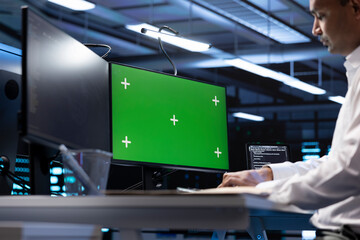 Indian man in data center using green screen computer to check for server performance issues. IT...