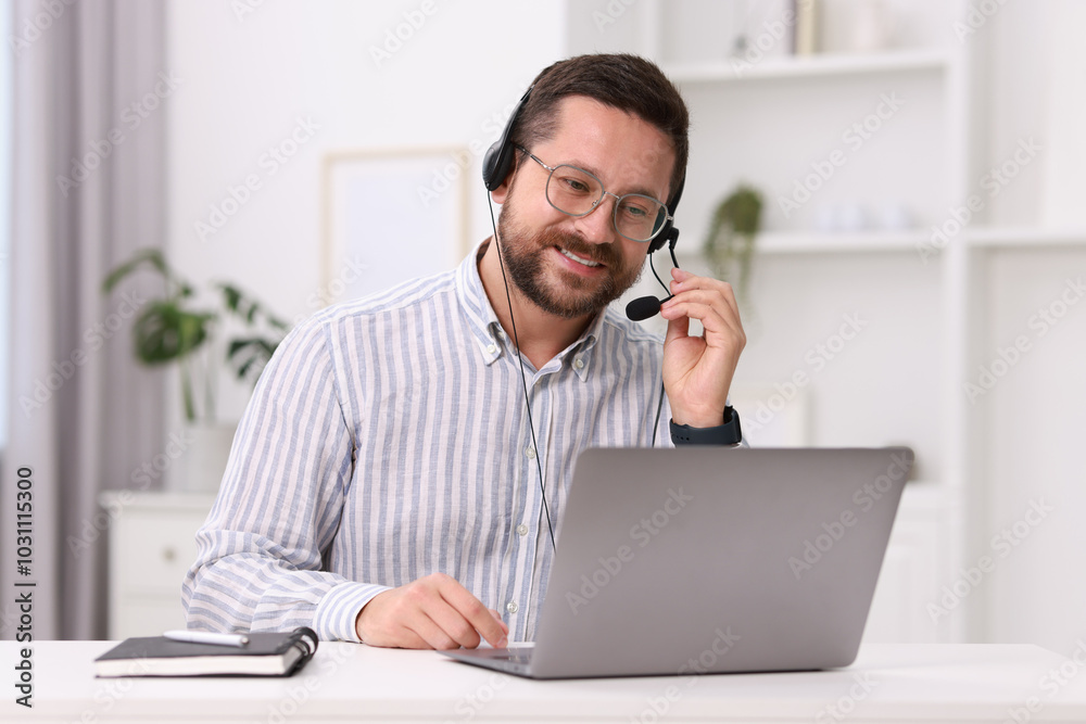 Wall mural Interpreter in headset having video chat via laptop at white table indoors