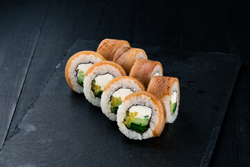 Sushi rolls with seared salmon, cream cheese, mango, cucumber and green onion.