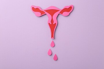 Menstruation. Paper uterus with drops on violet background, top view
