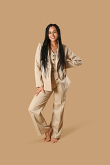 Stylish young African-American woman with braids on beige background