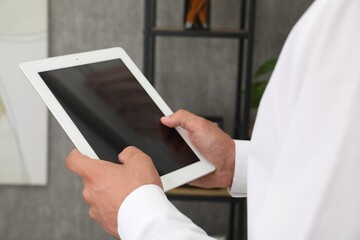 Businessman using tablet in office, closeup. Modern technology