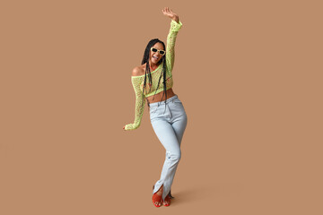 Cool young African-American woman with braids on beige background