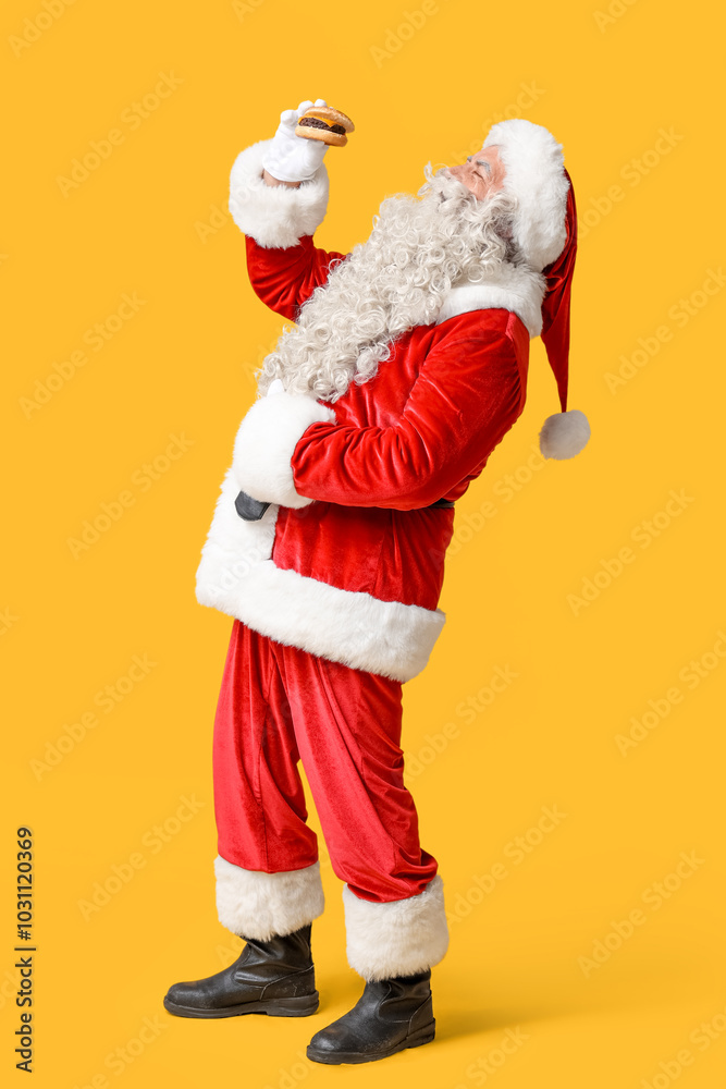 Wall mural Santa Claus with tasty burger on yellow background