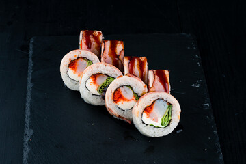 Set of sushi rolls with shrimp, bacon, cream cheese, tobiko caviar, lettuce and teriyaki sauce.