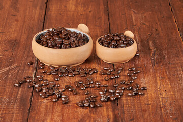 Close-up of freshly roasted coffee beans in a ceramic container on an old wooden table