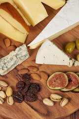 Round board with a wide variety of cheeses and other products to accompany a glass of red wine