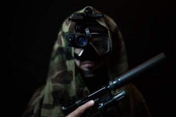 A combat swimmer with a night vision device and a pistol with a silencer in the semi-darkness on a...