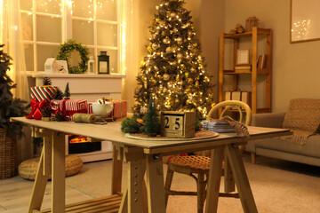 Calendar with date of Christmas, decor and presents on table in living room at night