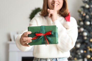Young woman with Christmas gift box at home, closeup