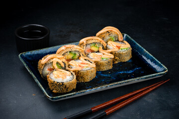 Fried sushi rolls with salmon fish, cream cheese, avocado and sauce.