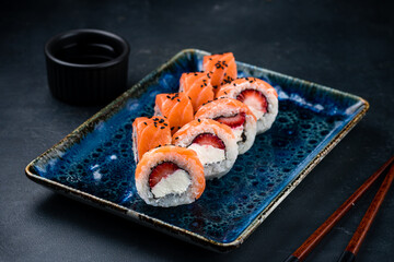 Set of sushi rolls with raw salmon fish, cream cheese, strawberry and sauce.
