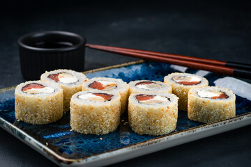 Sushi rolls with salmon, cream cheese, tamago omelet, sesame seeds and soy sauce.