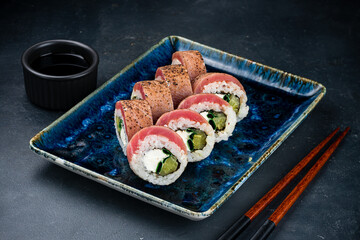 Set of Japanese sushi rolls with seared tuna, cream cheese, zucchini, soy sauce and chopsticks.