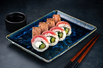 Sushi rolls with seared tuna, cream cheese, zucchini, soy sauce and chopsticks.