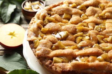 Homemade apple pie and ingredients on wooden table, closeup