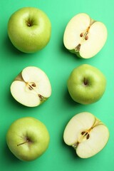 Flat lay composition with whole and cut apples on green background