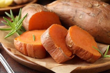 Tasty cooked sweet potatoes and rosemary on table, closeup