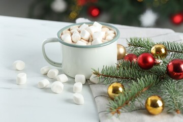 Tasty hot cocoa drink with marshmallows in mug and Christmas decor on white table, closeup