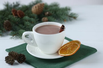 Yummy cocoa in cup and fir tree branches on white wooden table