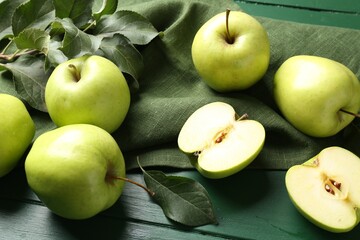 Ripe apples and leaves on green wooden table