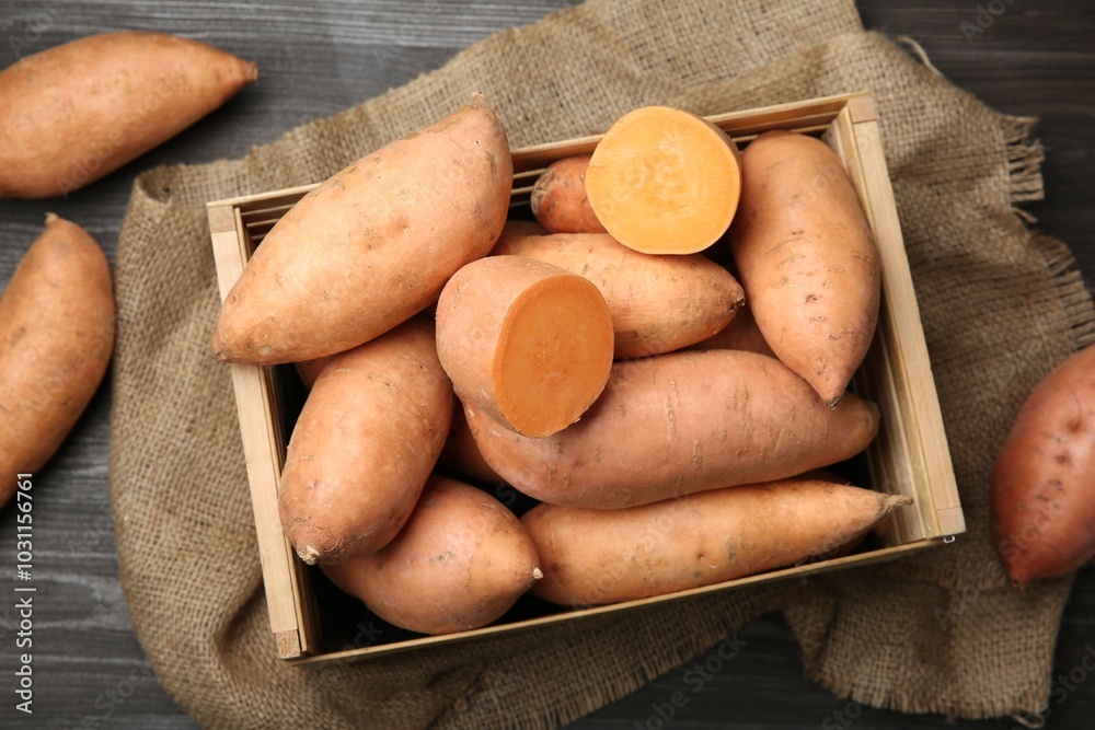 Poster Fresh raw sweet potatoes in crate on wooden table, top view