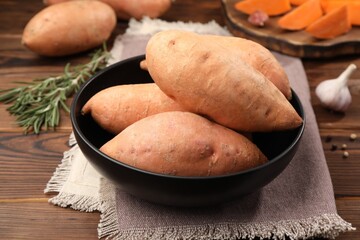 Fresh sweet potatoes in bowl on wooden table, closeup