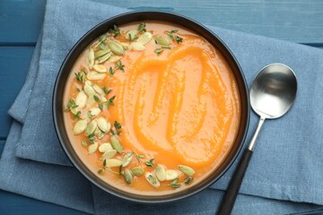 Delicious sweet potato soup with pumpkin seeds on blue wooden table, top view