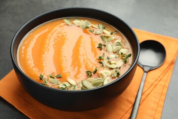 Delicious sweet potato soup with pumpkin seeds in bowl on grey table, closeup
