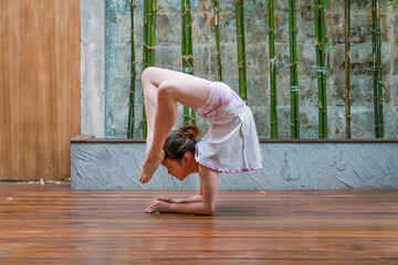 Pretty young female acrobats is posing. Gymnasts perform in a studio against a Japanese home...