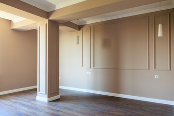 A large empty room with a white wall and a brown pillar
