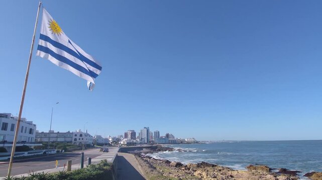 Flag of Uruguay with flagpole waving in wind. Uruguayan flag waving with the summer breeze. Punta de las Salinas, Punta del Este, Uruguay | 4K | Horizontal Video
