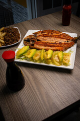 Grilled Trout with Green Tomato and Lettuce Salad: A beautifully presented dish showcasing perfectly grilled trout, served alongside a fresh green tomato and lettuce salad. Beside it, a plate of fried