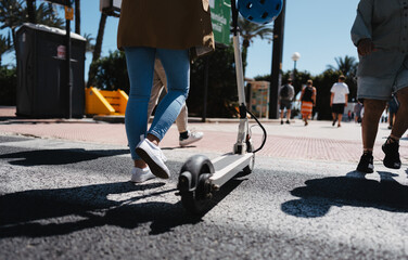 Woman push electric scooter and cross street © Novak