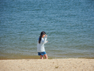 夏の海のビーチで散歩する一人の小学生の女の子の姿