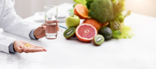 Cropped of afro woman nutritionist giving pills and glass of water to female patient, food...
