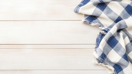 Obraz premium A cozy blue and white checkered fabric draped on a textured wooden surface, perfect for kitchen or rustic décor.