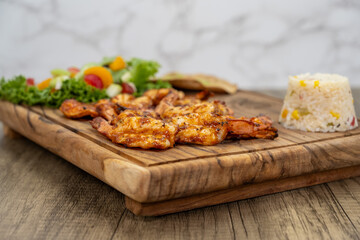 Spicy grilled diablo shrimp arranged on a wooden platter and served with salad for a delicious seafood meal.