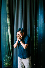 Fototapeta premium A Southeast Asian man is sneezing, capturing the moment of surprise on his face