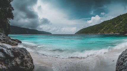 A pristine white sand beach with turquoise water, surrounded by lush green hills.  The sky is a dramatic mix of clouds and sun, creating a beautiful and serene scene.
