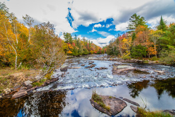 Raquette River Long Lake NY ADK surrounded by brilliant fall foliage on a partly cloudy day