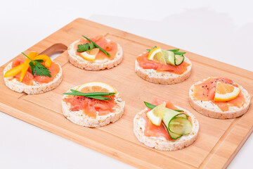 Rice Cake Sandwiches with Fresh Salmon, Cucumber, Lemon and Greens on Bamboo Cutting Board. Diet Food. Quick and Healthy Sandwiches. Crispbread with Fresh Fillings. Healthy Dietary Snacks